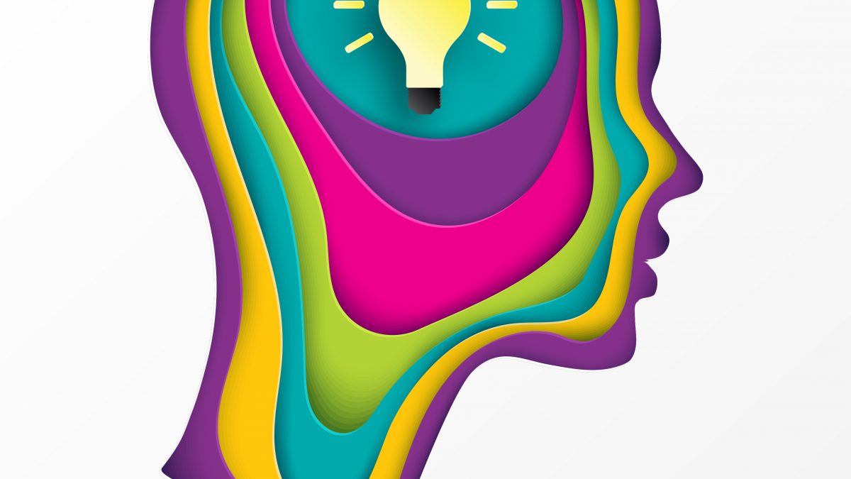 A colorful paper cut out of a head with an idea light bulb inside.