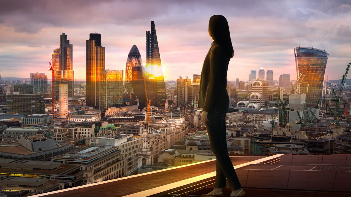 A person standing on the edge of a building looking at a city.