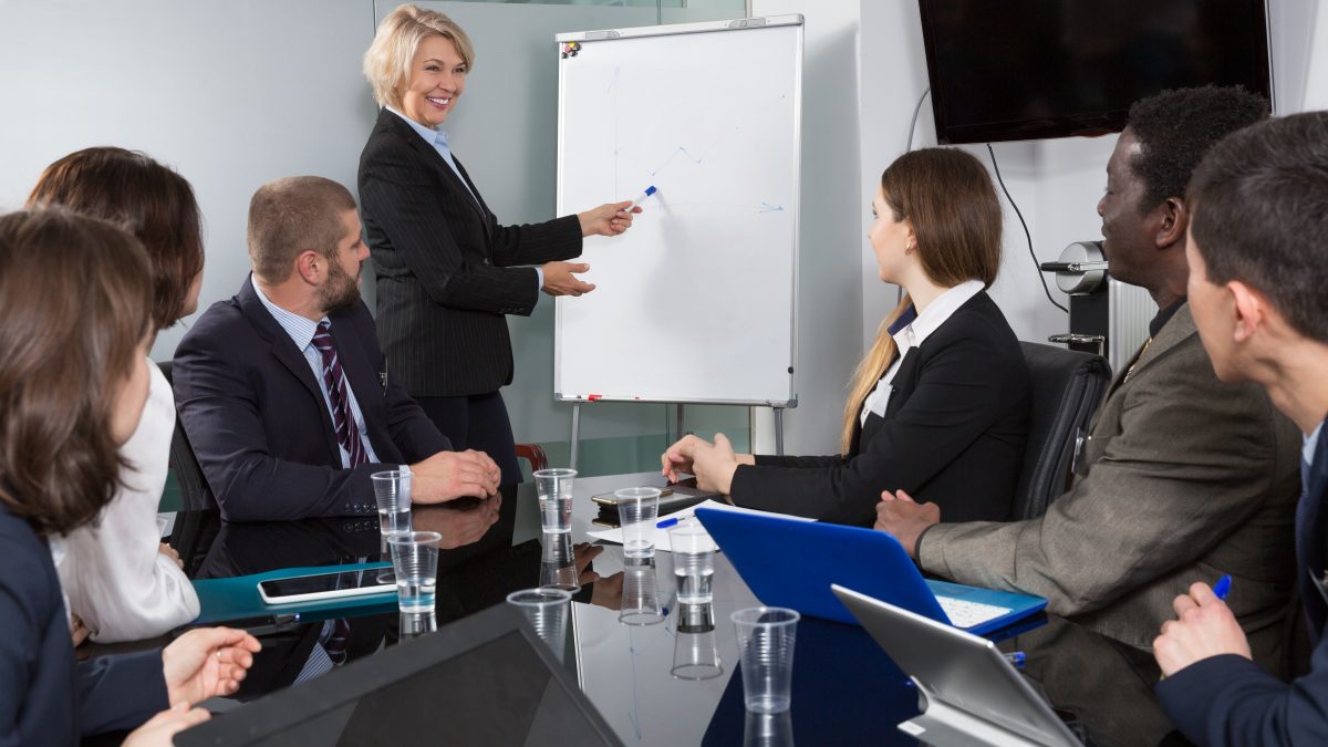 A woman in business attire is giving a presentation.